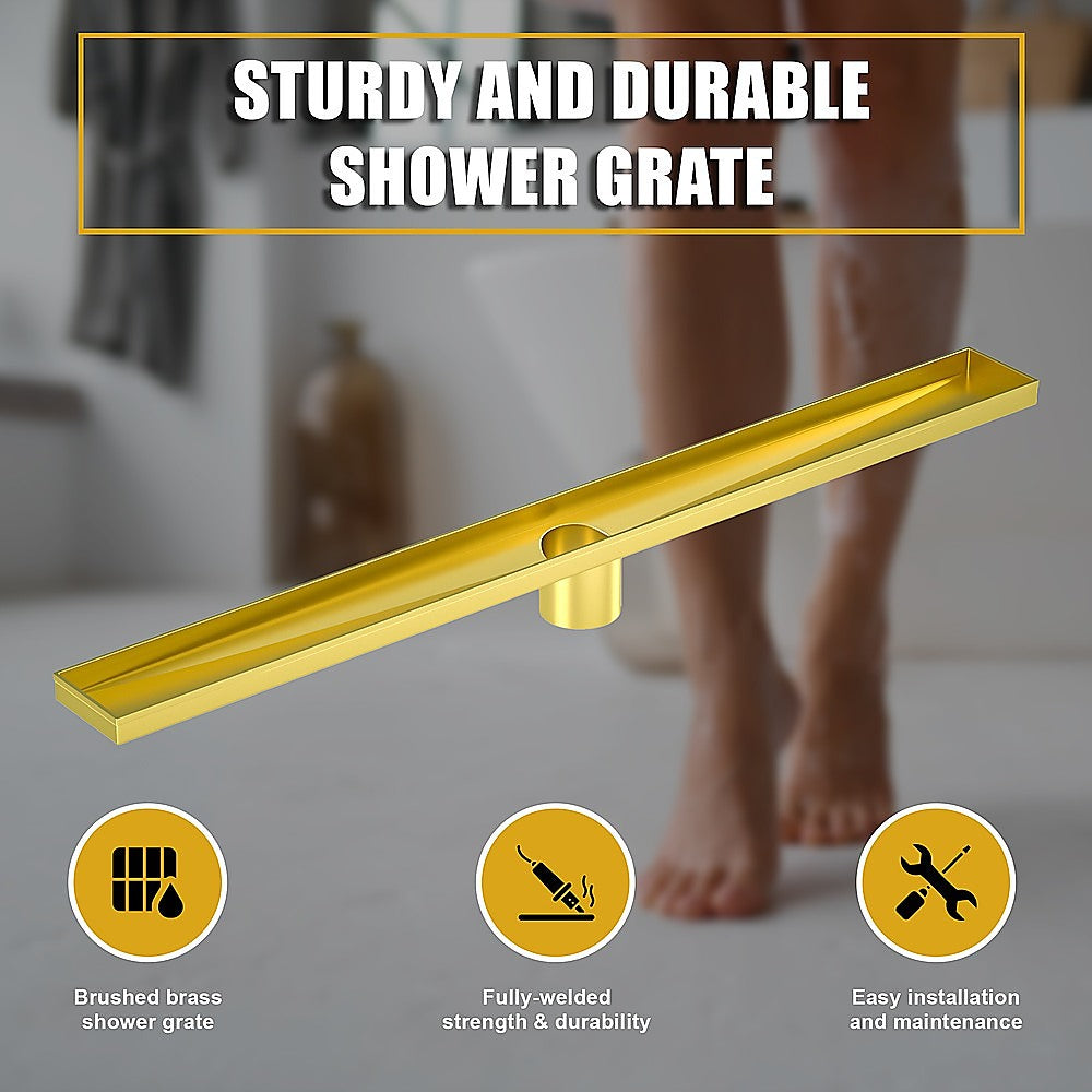 Brushed brass linear shower grate with center outlet, shown above shower area