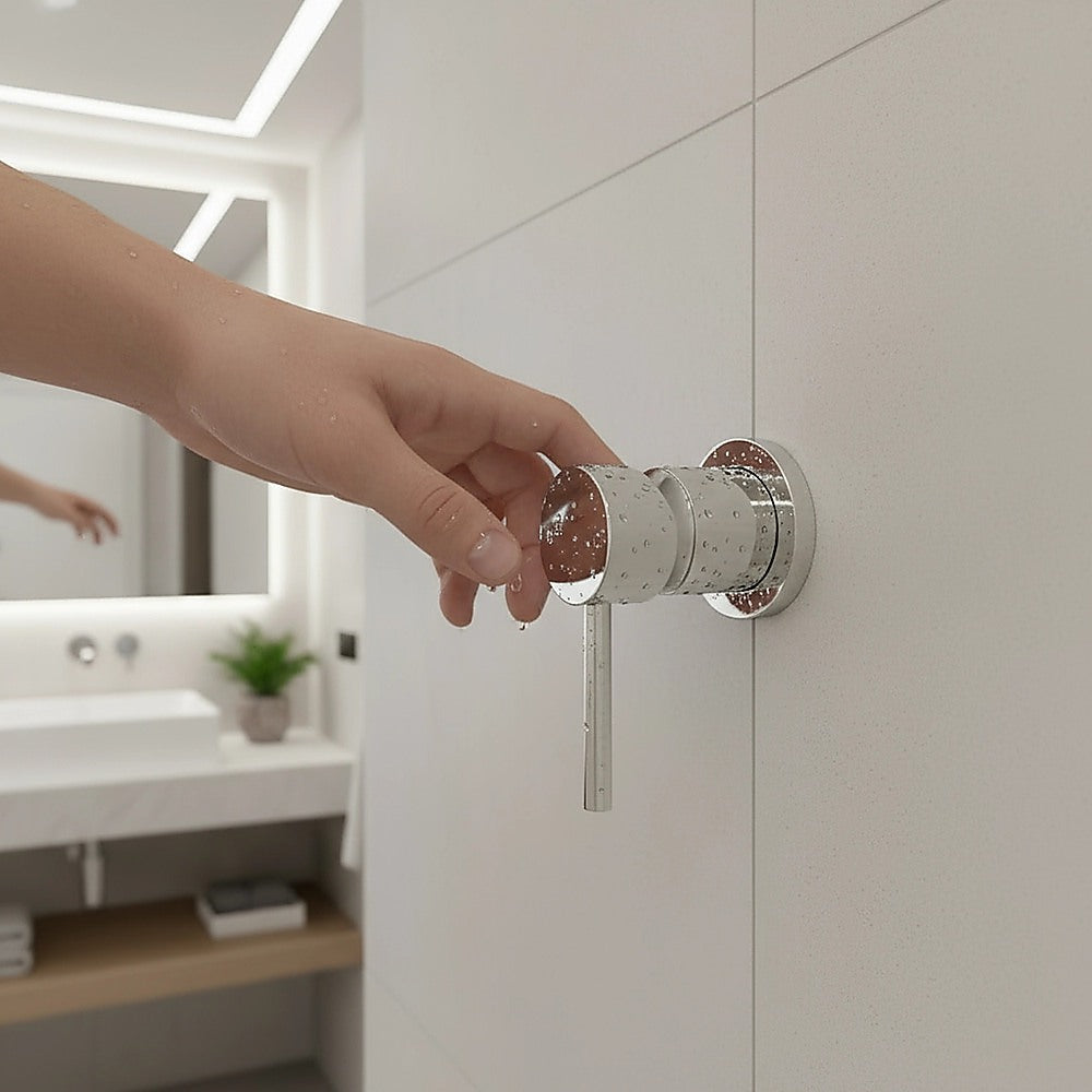 Hand turning a chrome shower bath mixer tap handle mounted on a wall
