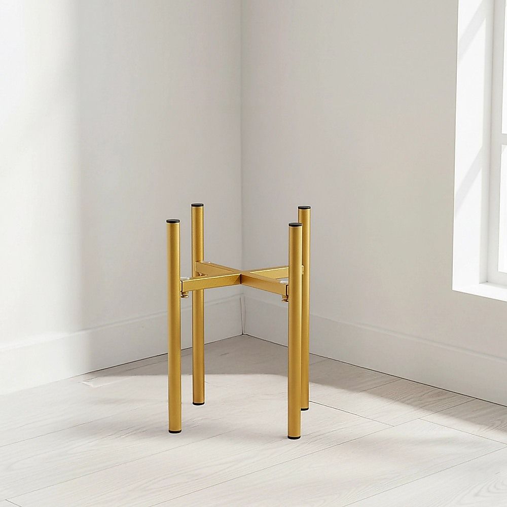 Gold metal plant stand with four legs in an indoor corner