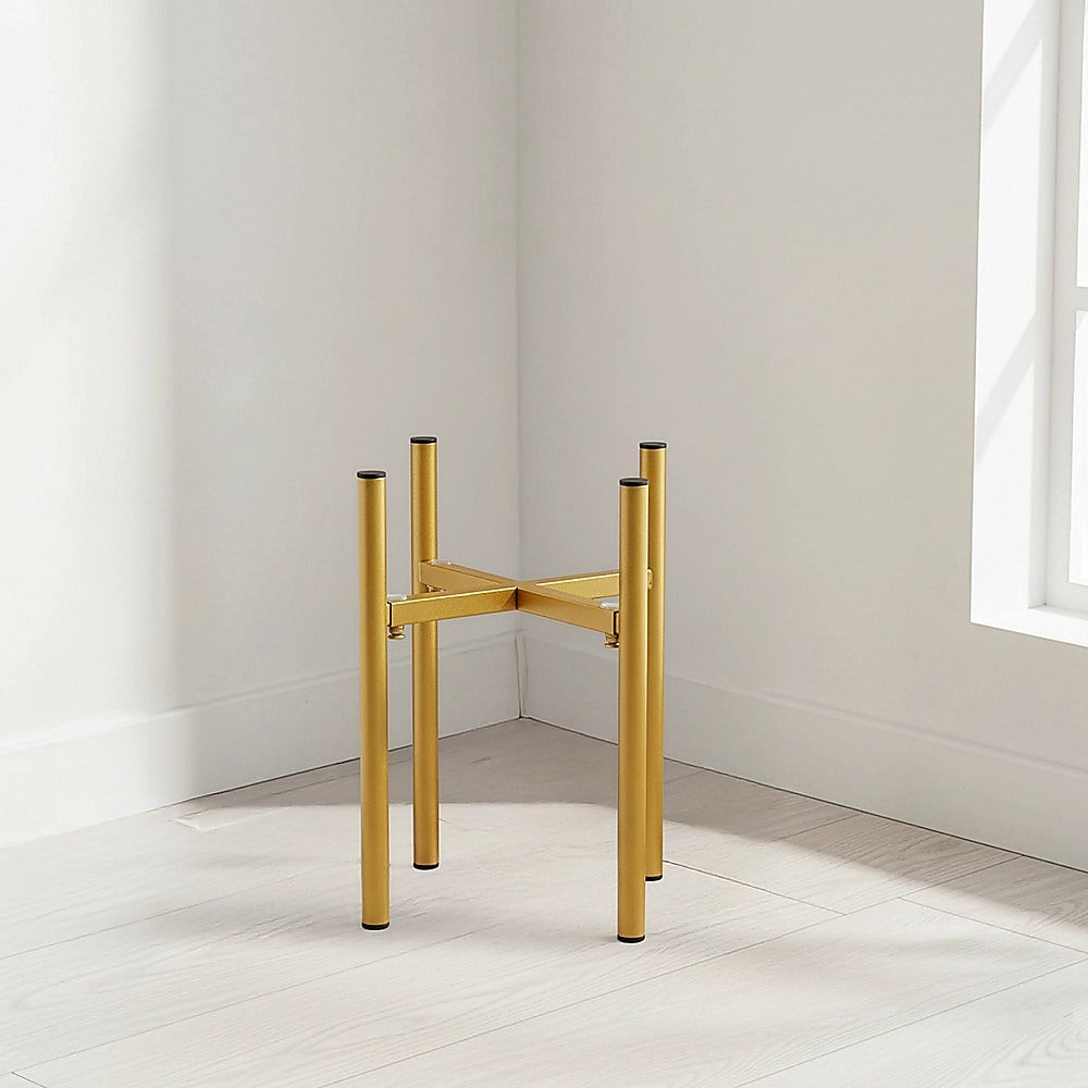 Gold adjustable metal plant stand with four legs and open top shelf in corner space