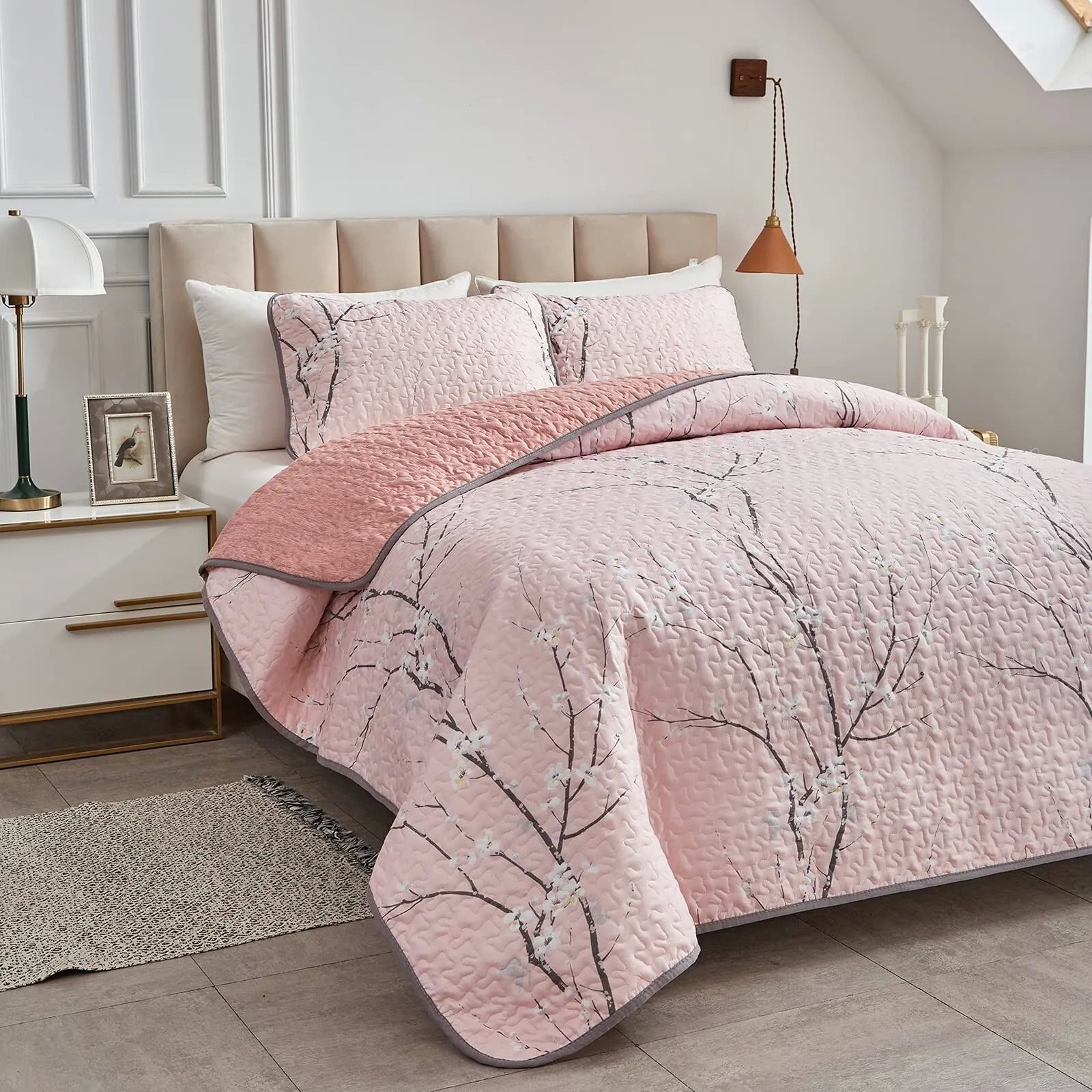 Quilted bed set with light pink coverlet and pillowcases, branch floral design