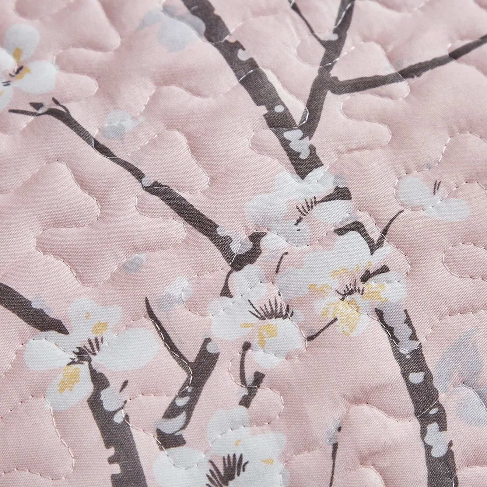 Quilted fabric detail in light pink with dark branches and small white flowers
