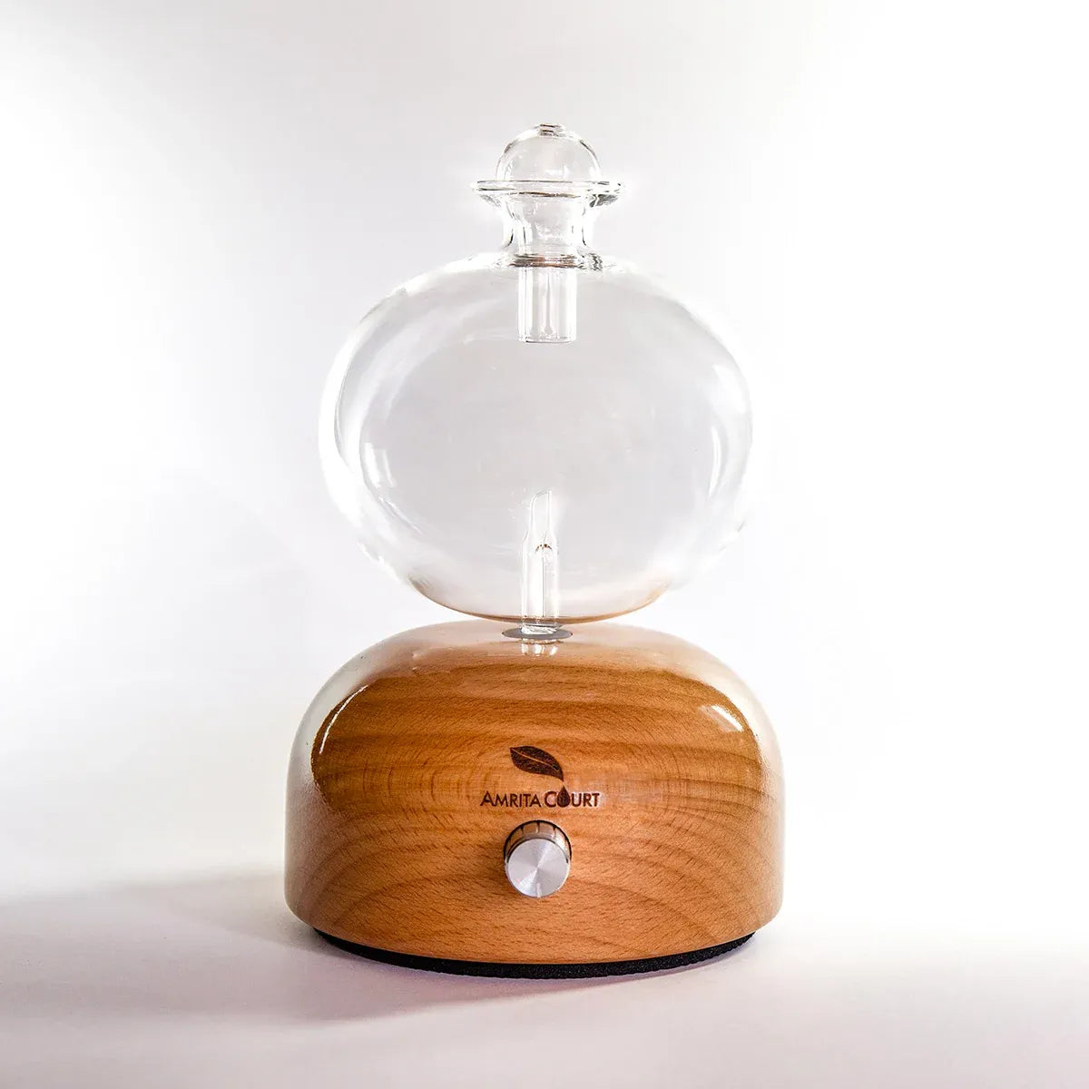 Glass essential oil nebuliser with clear globe and warm wood base, control dial