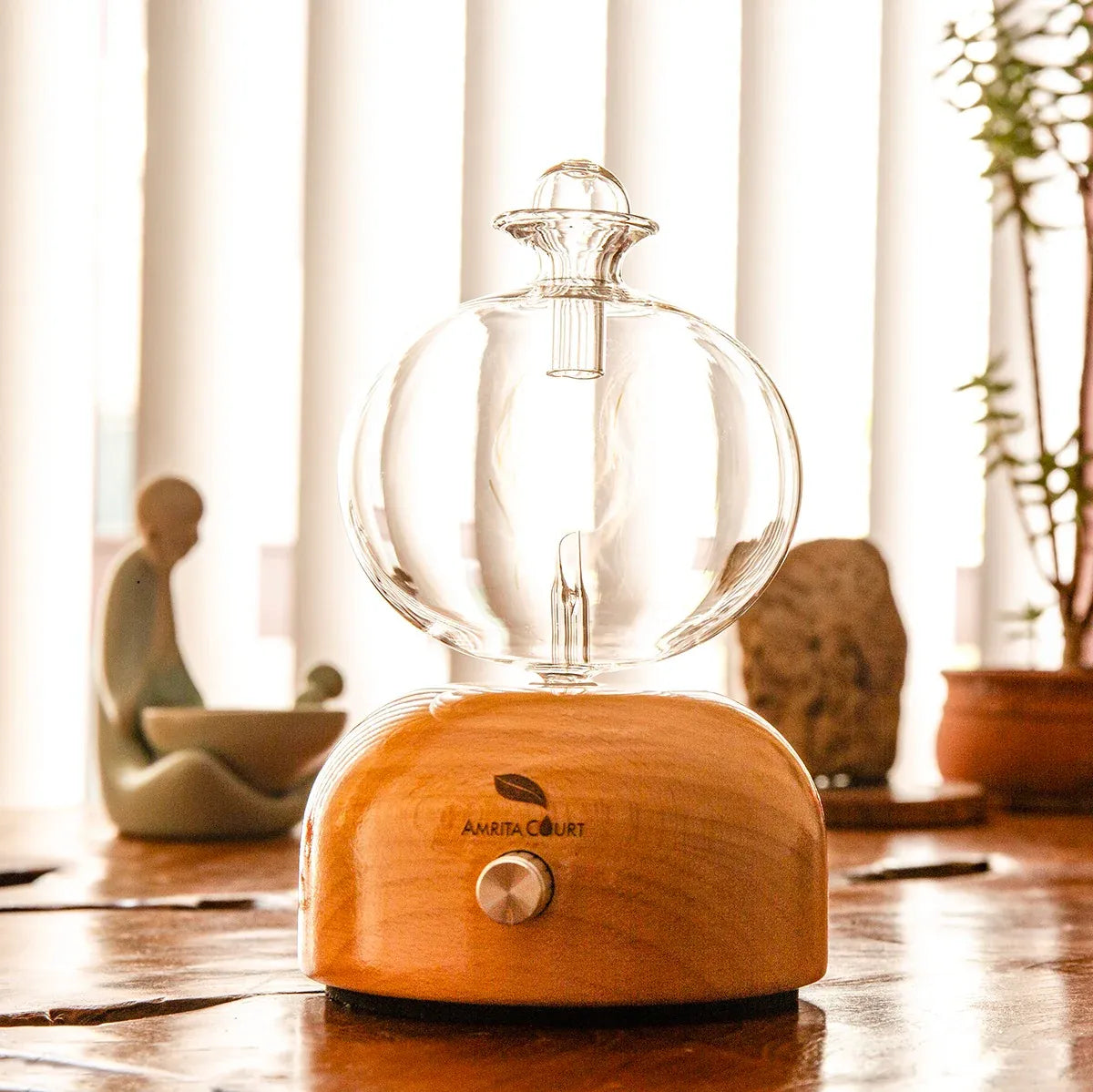 Glass globe essential oil diffuser on warm wood base with round metal dial