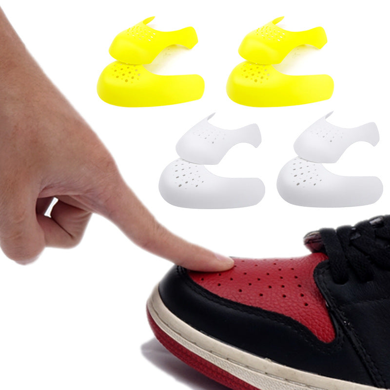 Shoe crease protectors being fitted on a red-and-black sneaker; white and yellow pairs
