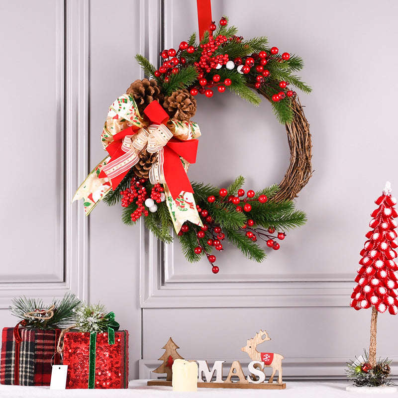 Christmas wreath with pine branches, red berries, pinecones, and ribbon bow