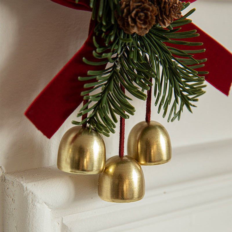 Close-up evergreen door ornament with gold bells and red hanging ribbon