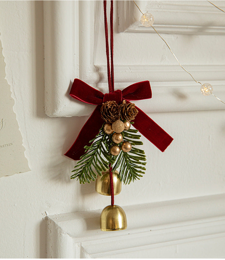 Hanging Christmas ornament with red velvet bow, pinecones, evergreen sprigs, and gold bells