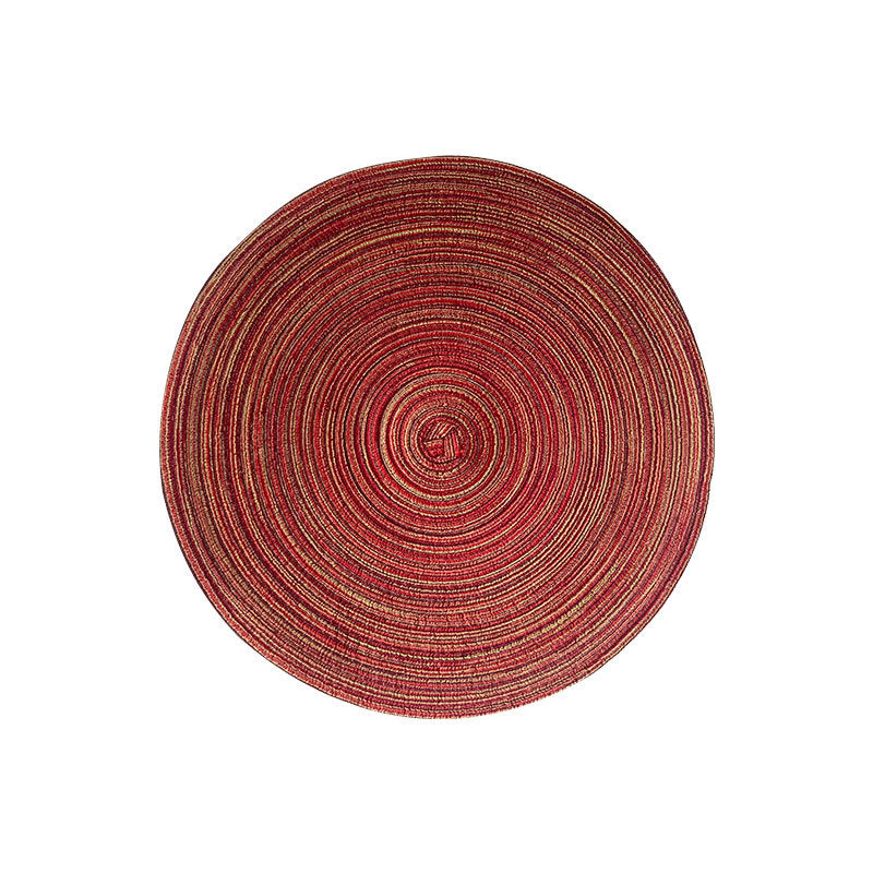 Red round woven placemat with braided spiral pattern for a dining table.