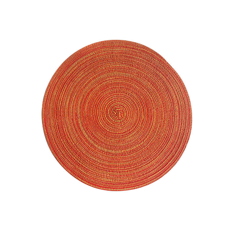 Round woven placemat in orange with concentric spiral weave pattern