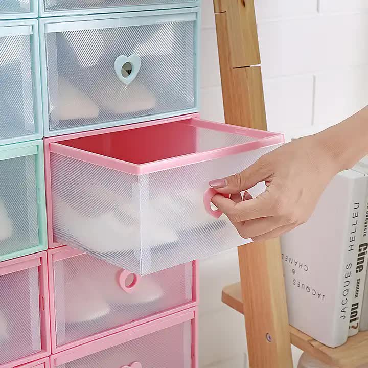 Pink transparent shoe storage box with heart handle, held open by a hand