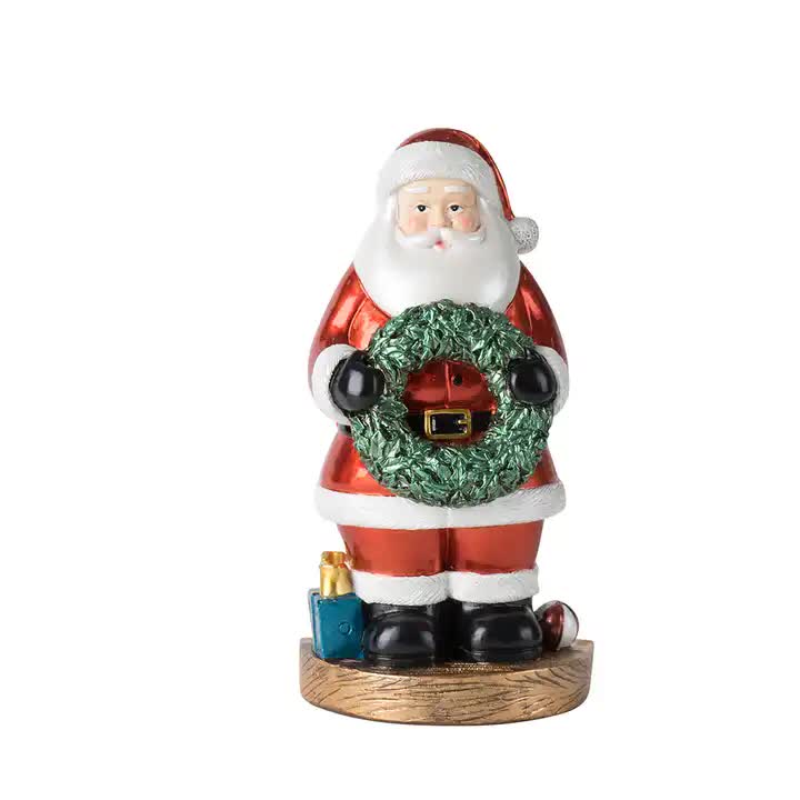 Santa Claus figurine with green wreath and red coat, on round wooden base