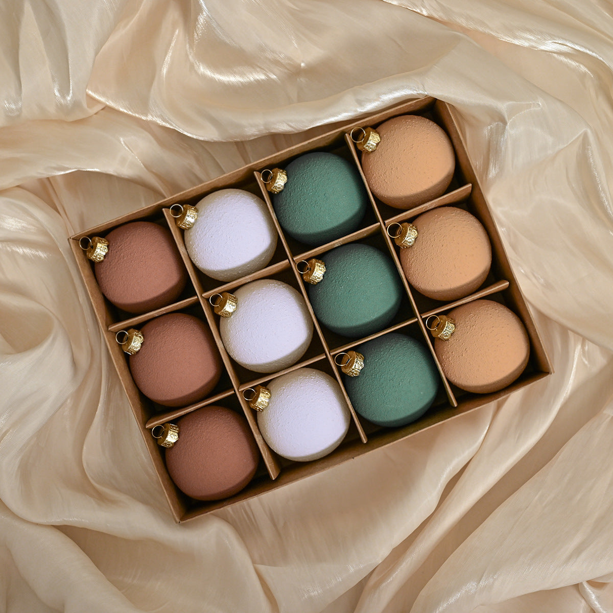 Set of matte Christmas ornaments in pastel colors with gold caps, shown in a box