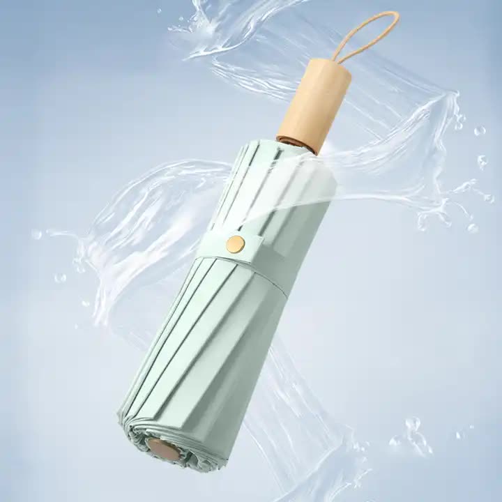 Folding umbrella with mint green fabric cover and light wood handle, closed