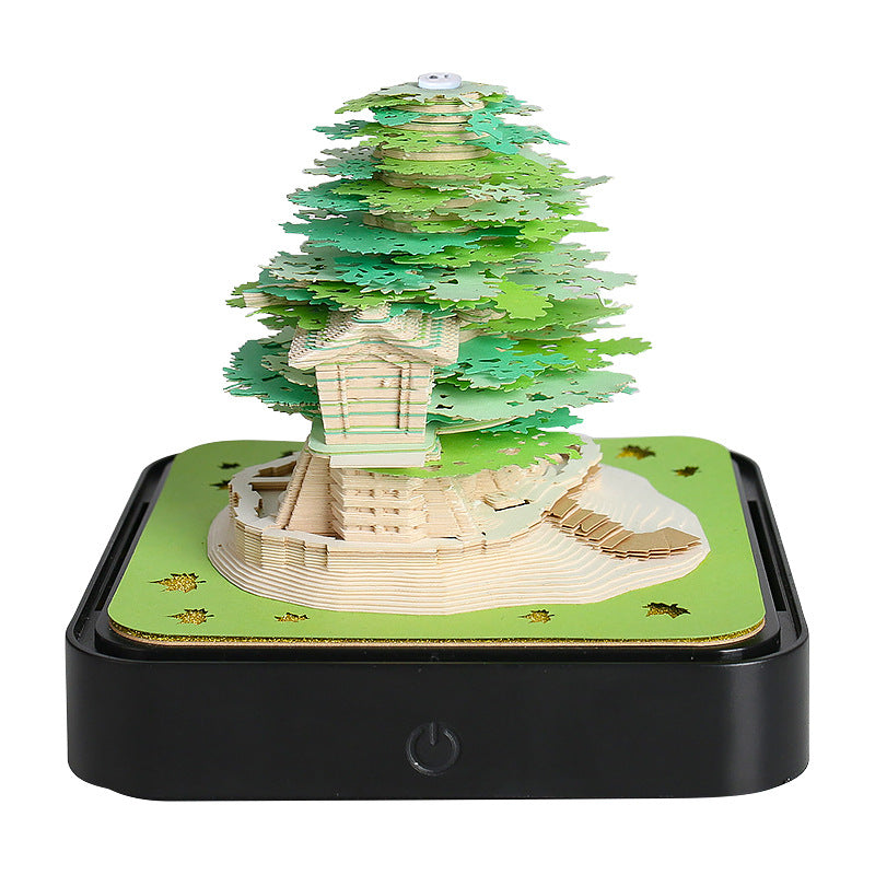 Green 3D paper tree night light with glowing base, black base and power button.