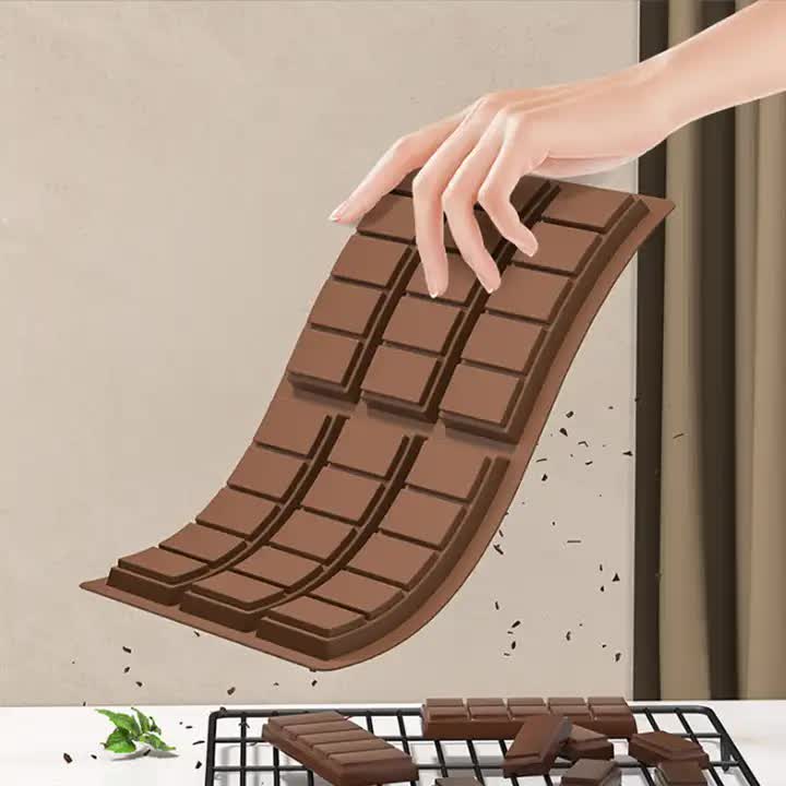 Brown silicone chocolate bar mold being bent to release shaped cavities