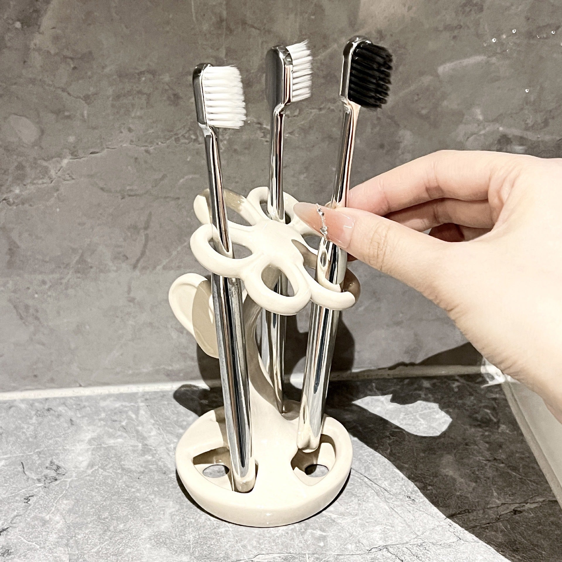 White ceramic toothbrush holder with circular base holding three toothbrushes