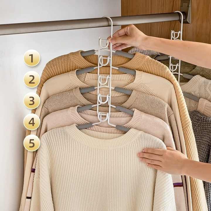 Multi-layer foam clothing hangers on a rack, holding cream and tan sweaters