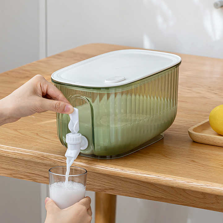 Green cold drink dispenser pitcher with white lid and spigot, pouring into a glass