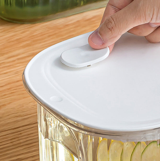 White lid on a clear juice dispenser tank with a rounded handle detail