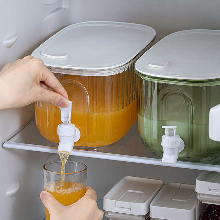 Two refrigerated juice dispensers in a white cabinet, filling cups via spigots
