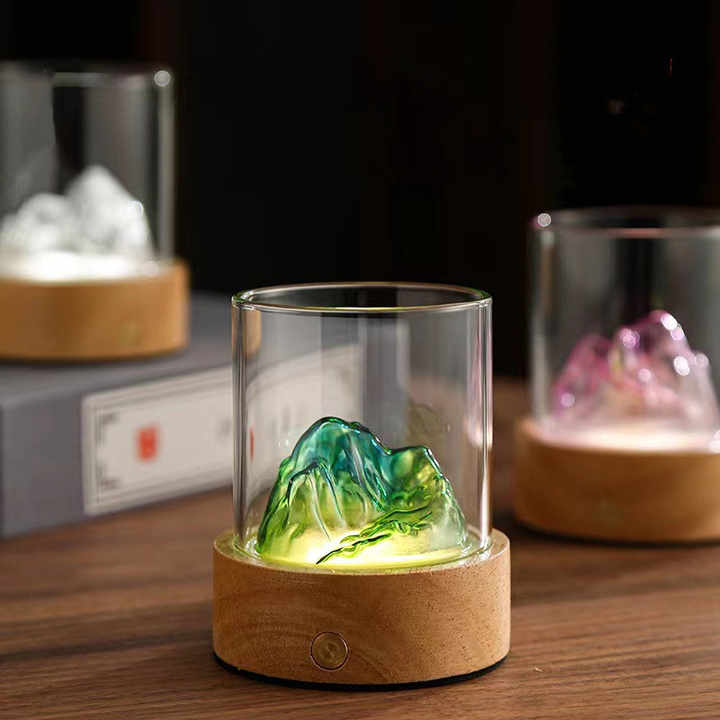 Glass mountain night light with green glowing lamp inside glass cylinder and cork base