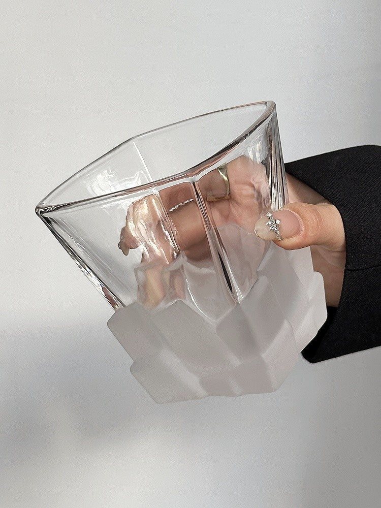 Textured frosted ice cube tumbler glass with clear rim, held at an angle