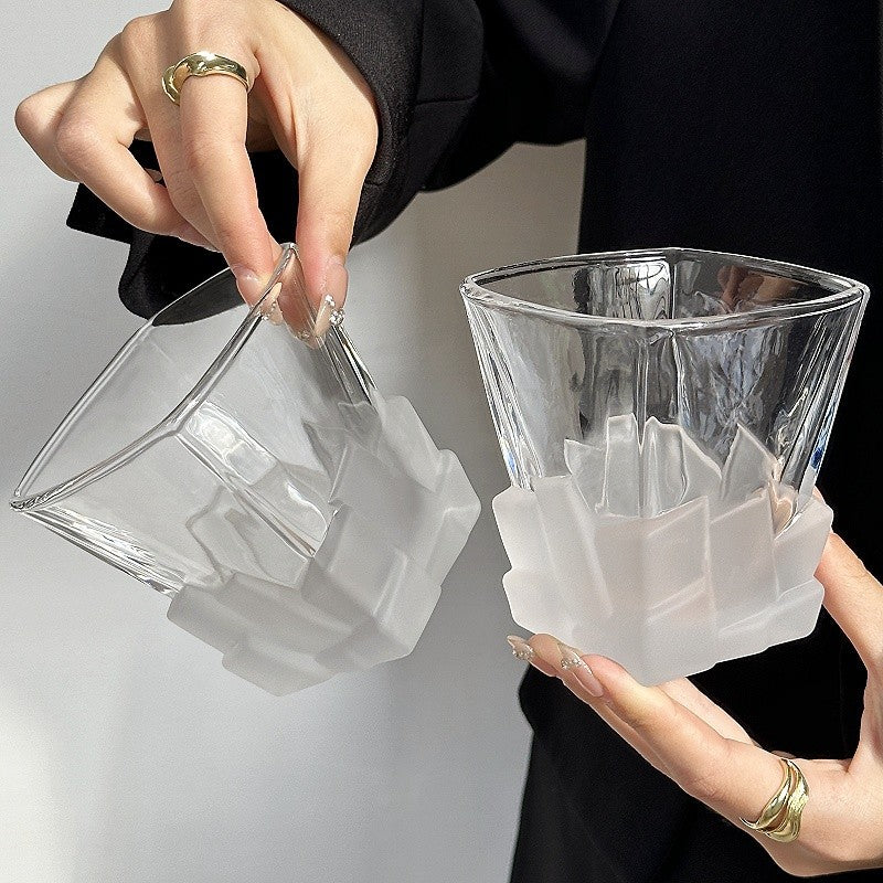 Clear frosted ice-cube textured glass tumbler with white faceted bottom, held