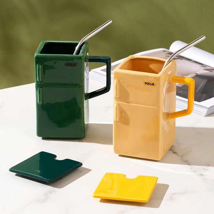 Green and yellow ceramic mugs with straws and flip lids, rectangular design