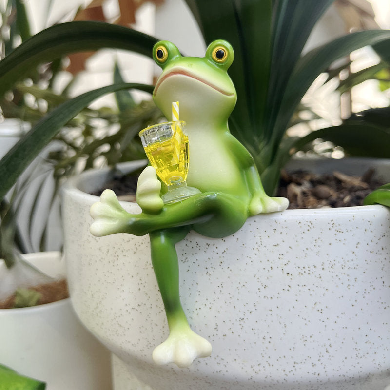 Green frog pot hanger ornament with crossed legs, holding yellow glass