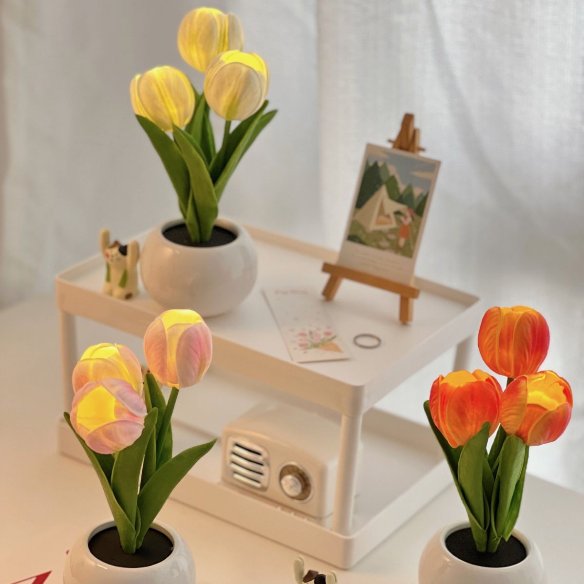Multiple tulip night lights with yellow blooms in ceramic pots on a side table