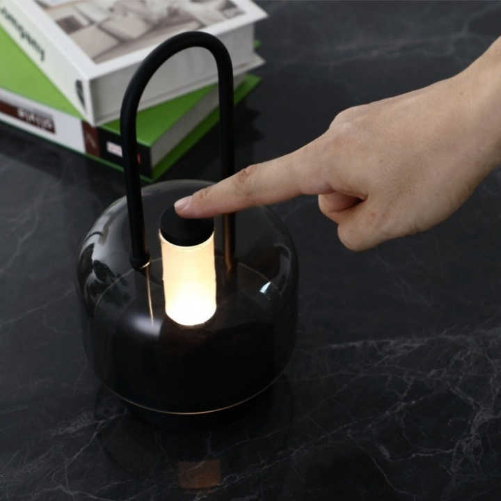 Portable LED lantern with smoked glass body, glowing inner bulb, touch-style top