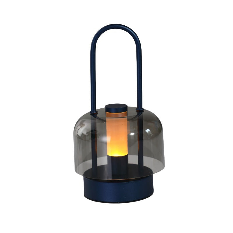 Dark blue portable LED lantern with clear glass shade, black handle, warm light glowing