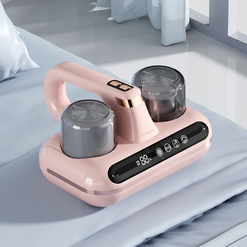 Pink wireless mite vacuum cleaner with two dust cups on a mattress surface