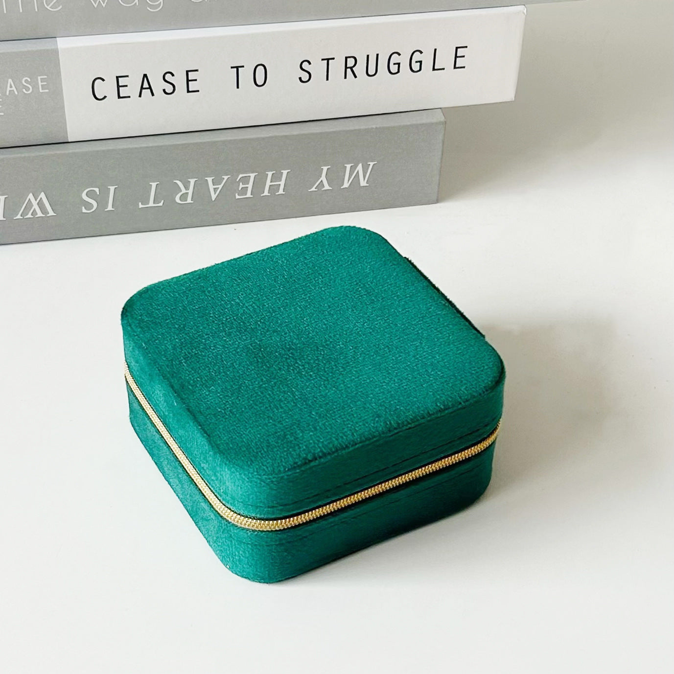Green portable travel jewelry box with zip closure, soft top, and compact shape.