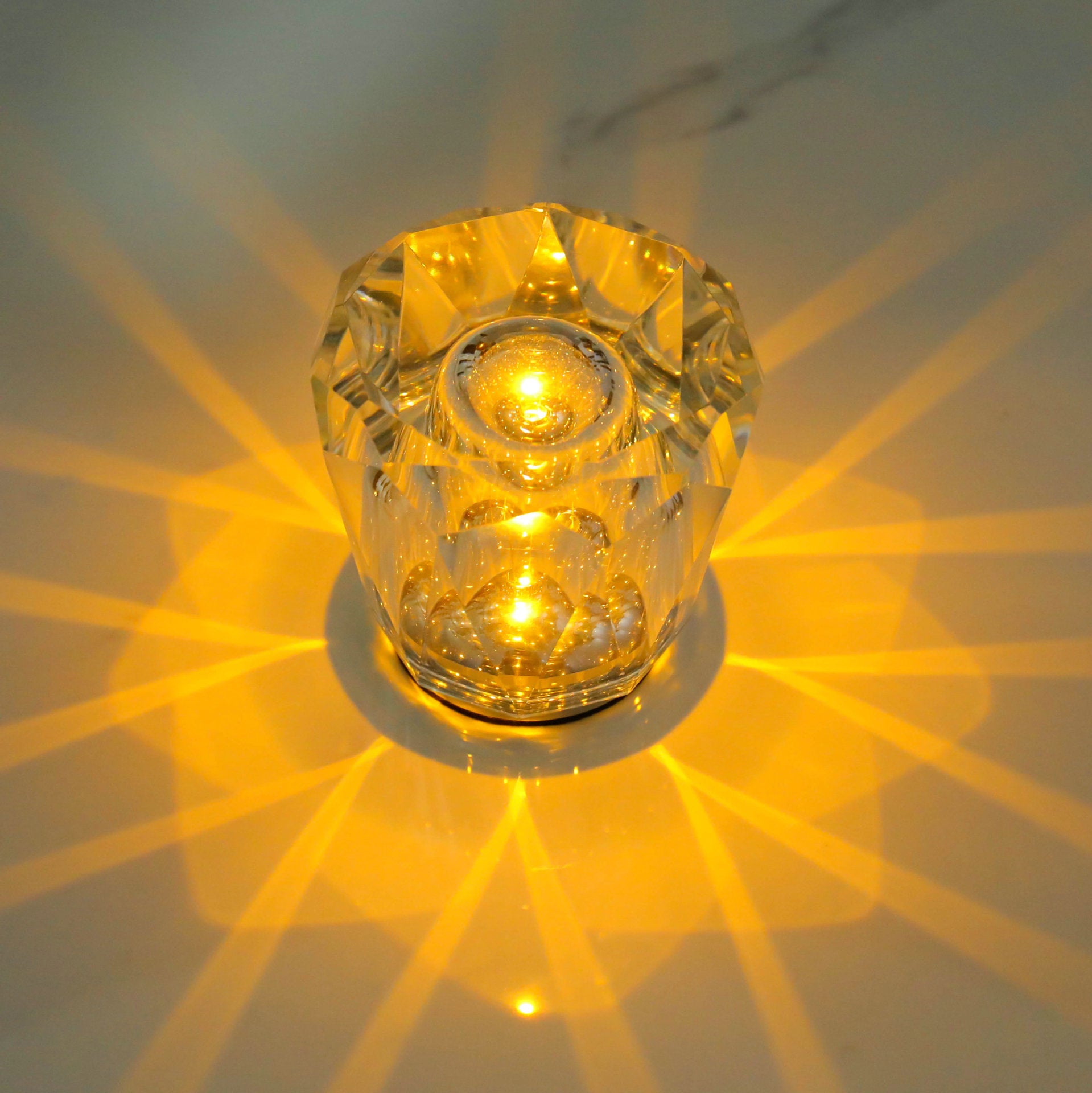 Crystal LED table lamp with faceted clear body and warm starburst glow