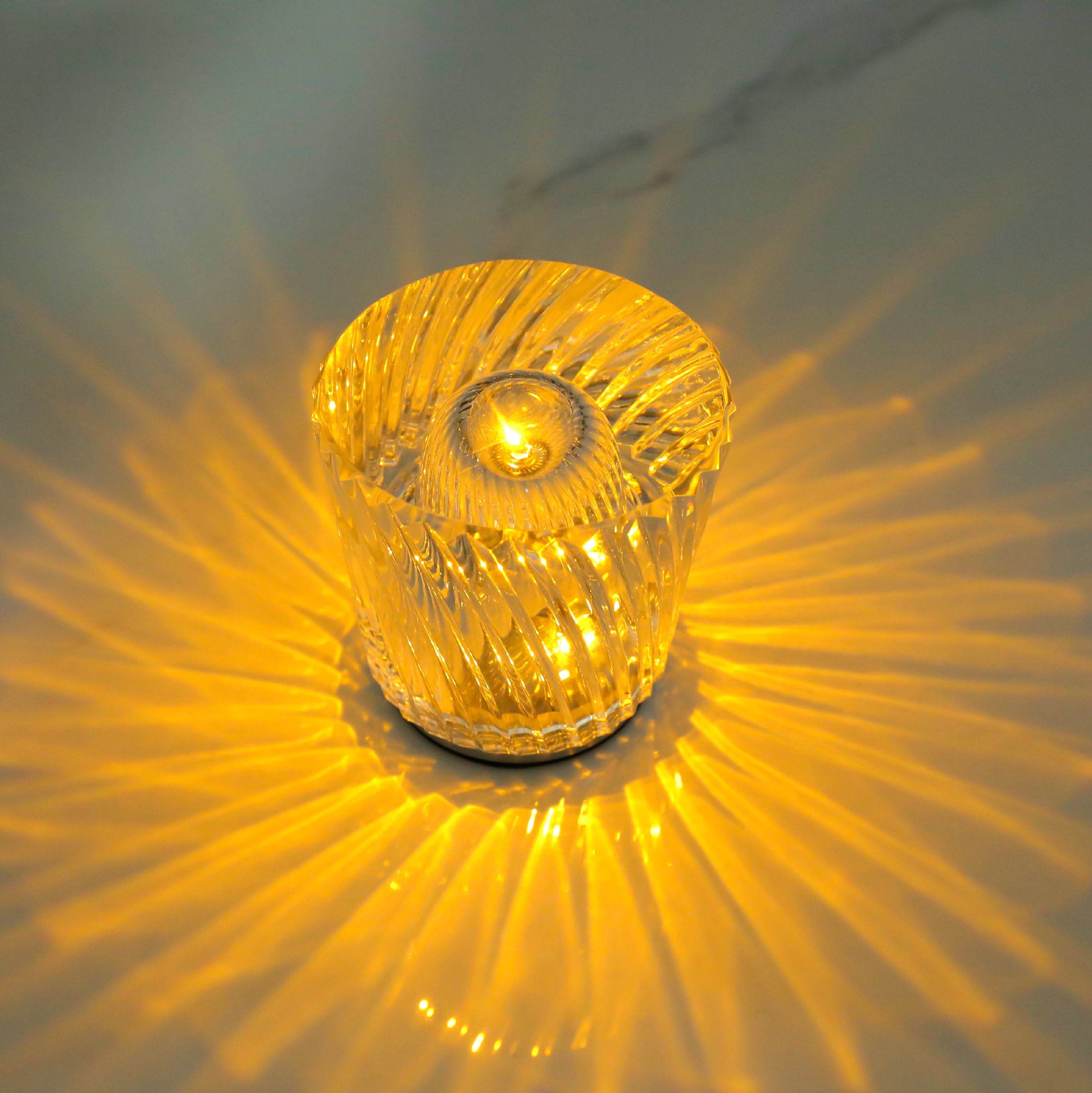 Amber crystal LED table lamp with faceted sides and glowing center bulb, starburst effect