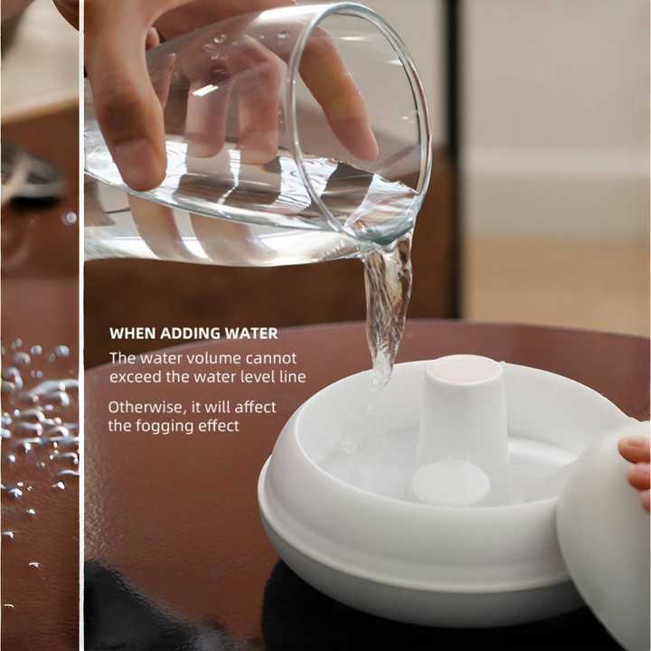 Ultrasonic aroma diffuser tank while water is poured in from a glass