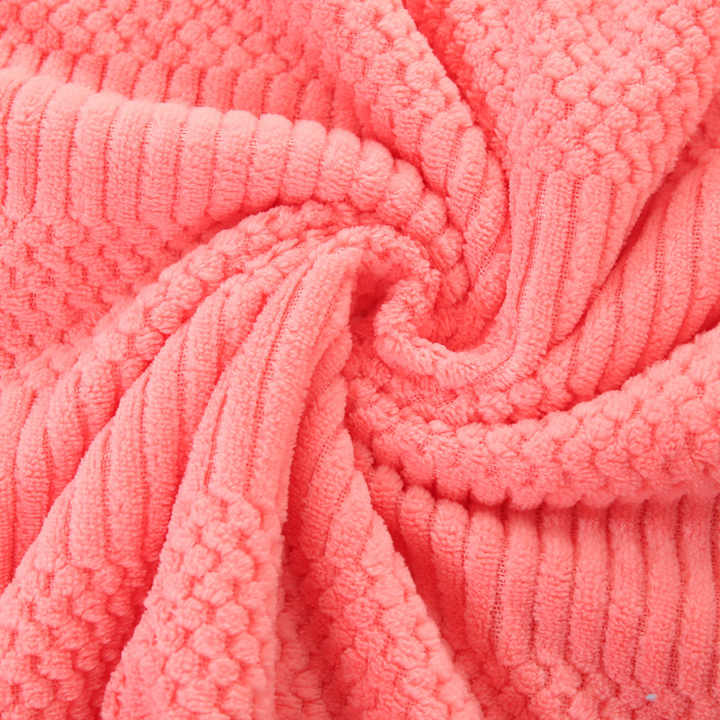 Coral fleece towel fabric close-up, textured looped surface in coral pink
