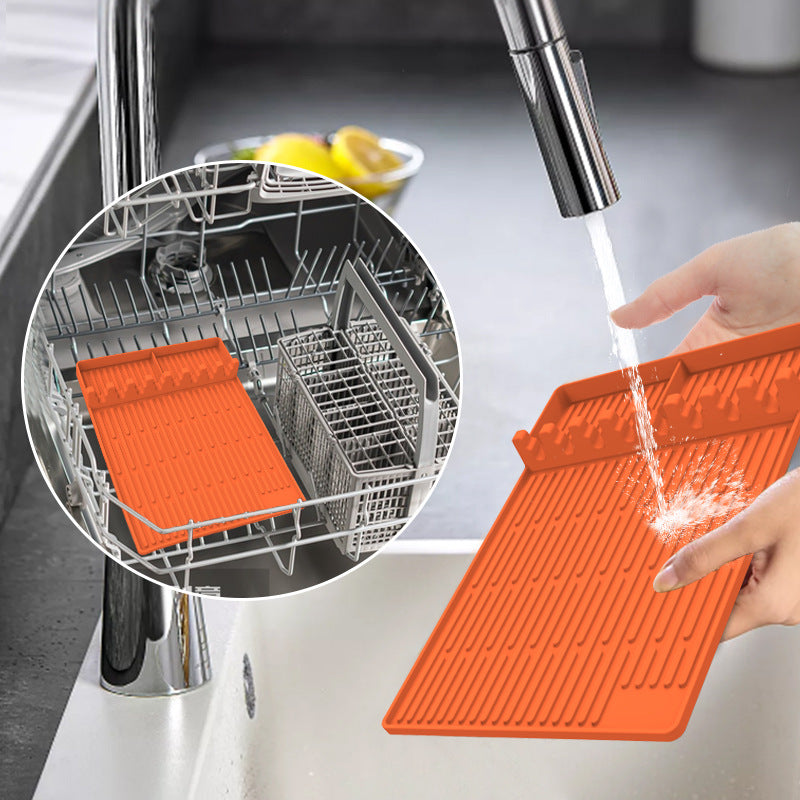Orange silicone grilling mat being cleaned, with ridged surface and raised edges