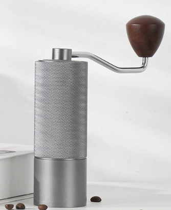 Manual coffee grinder with silver metal body and wooden hand crank, adjustable burr