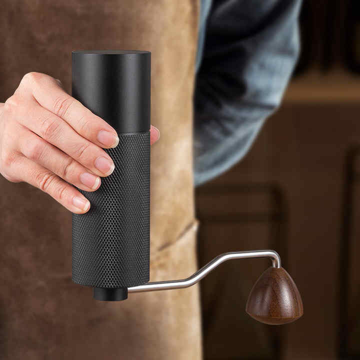 Manual coffee grinder with dark textured body, wooden handle, and metal crank lever