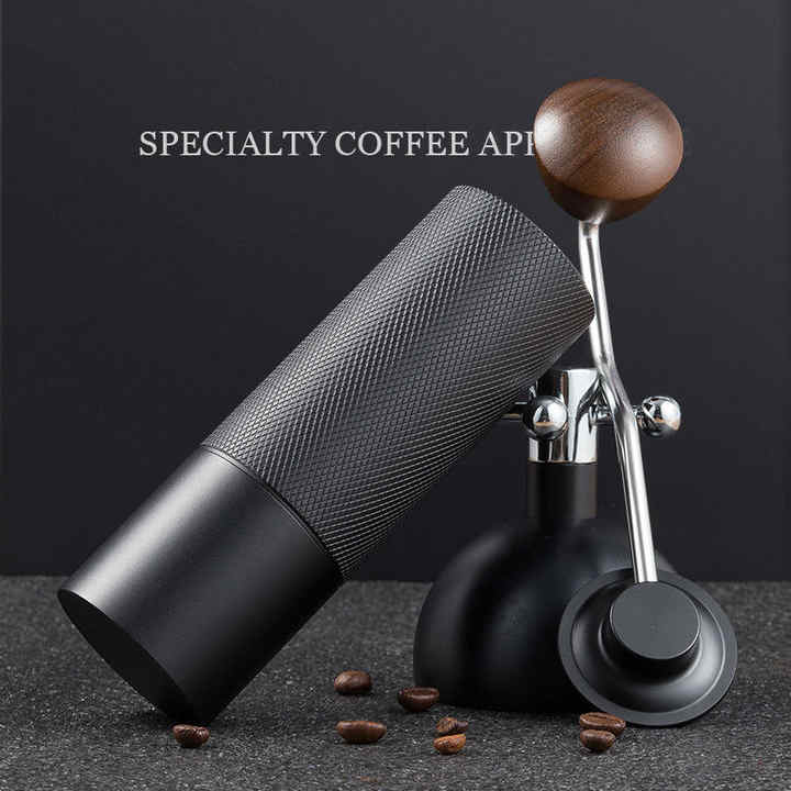 Manual coffee grinder with dark textured cylinder and wooden knob on metal stand