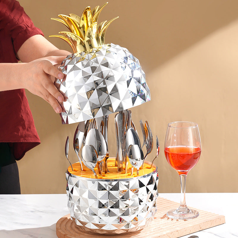 Pineapple-shaped cutlery container with silver utensils, diamond pattern, shown with hand