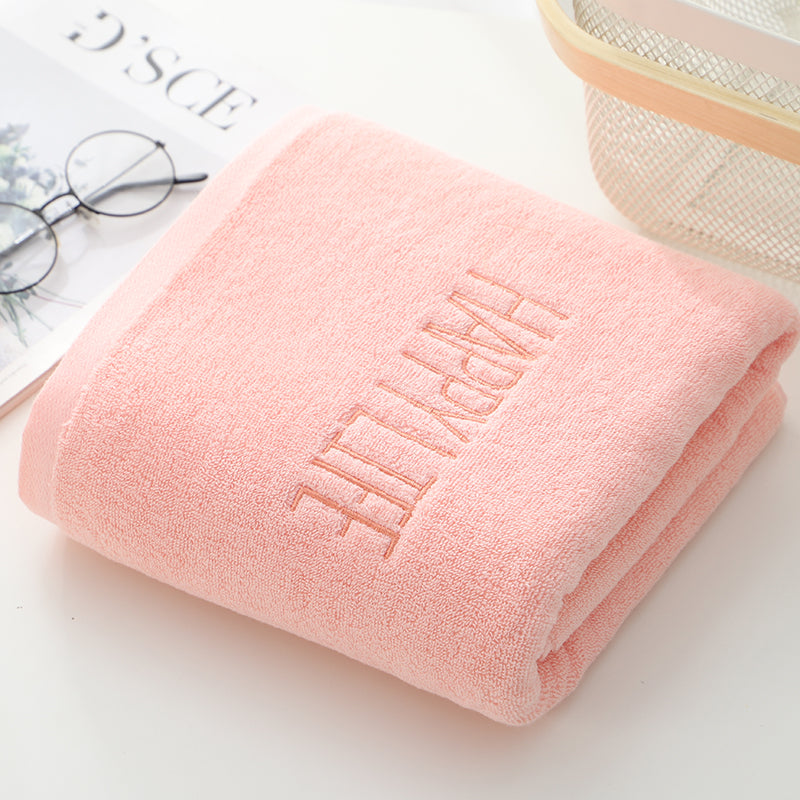 Pink bath towel, folded with embroidered 'Happy' lettering