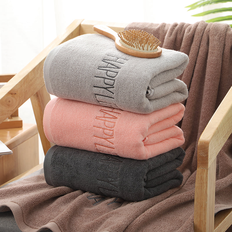 Stack of bath towels in gray and pink, with “HAPPY” embroidery on dark gray towel