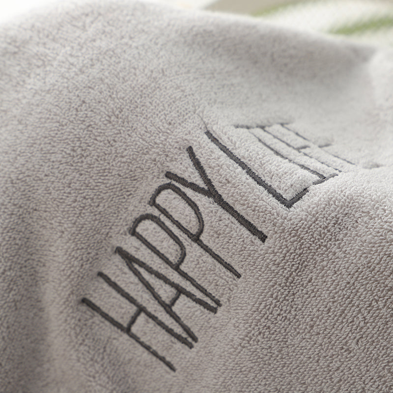 Light gray bath towel with “HAPPY” embroidered lettering on textured terry