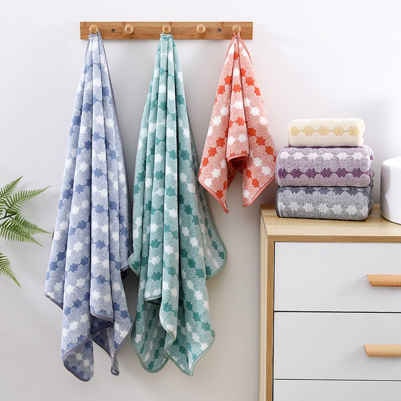 Purple coral fleece towel set with hanging patterned towels and stacked folded towels