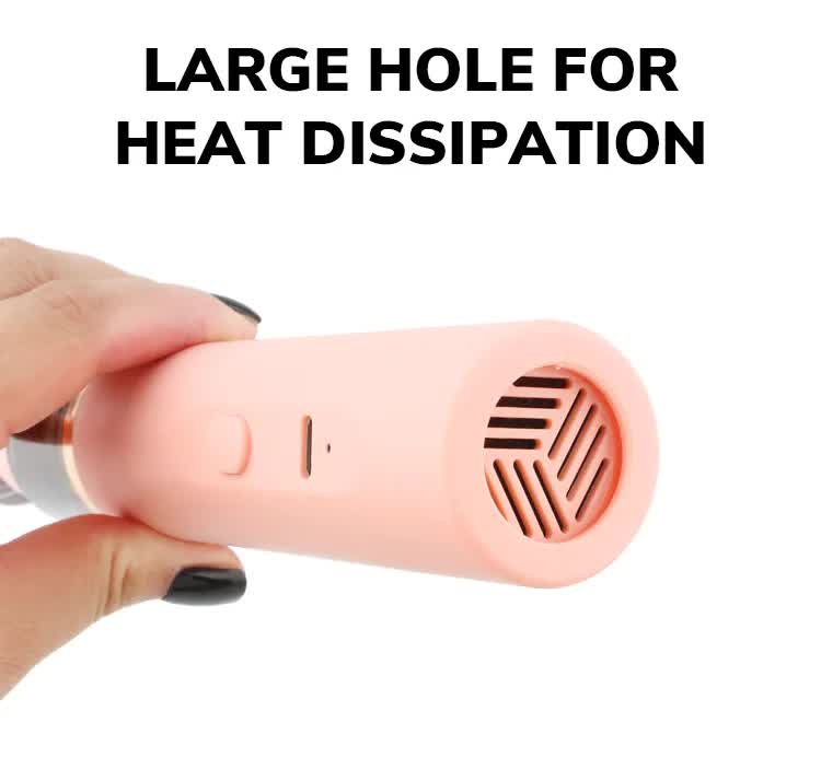 Pink handheld dust vacuum with vented air outlet, held in hand