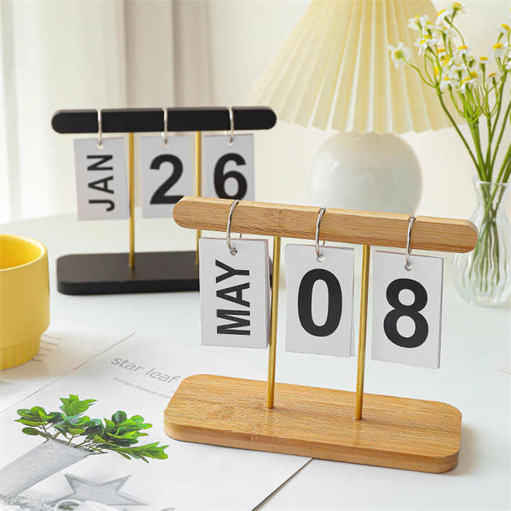 Desktop wooden flip calendar on light wood base, black top bar with JAN 26 and MAY 08